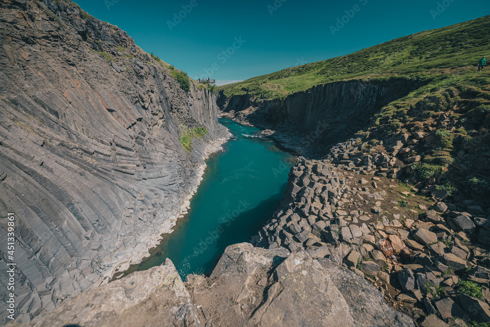 Amazing Studlagil canyon with high basalt columns in Iceland on a summer day. High perspective viewed from one of the basalt columns.