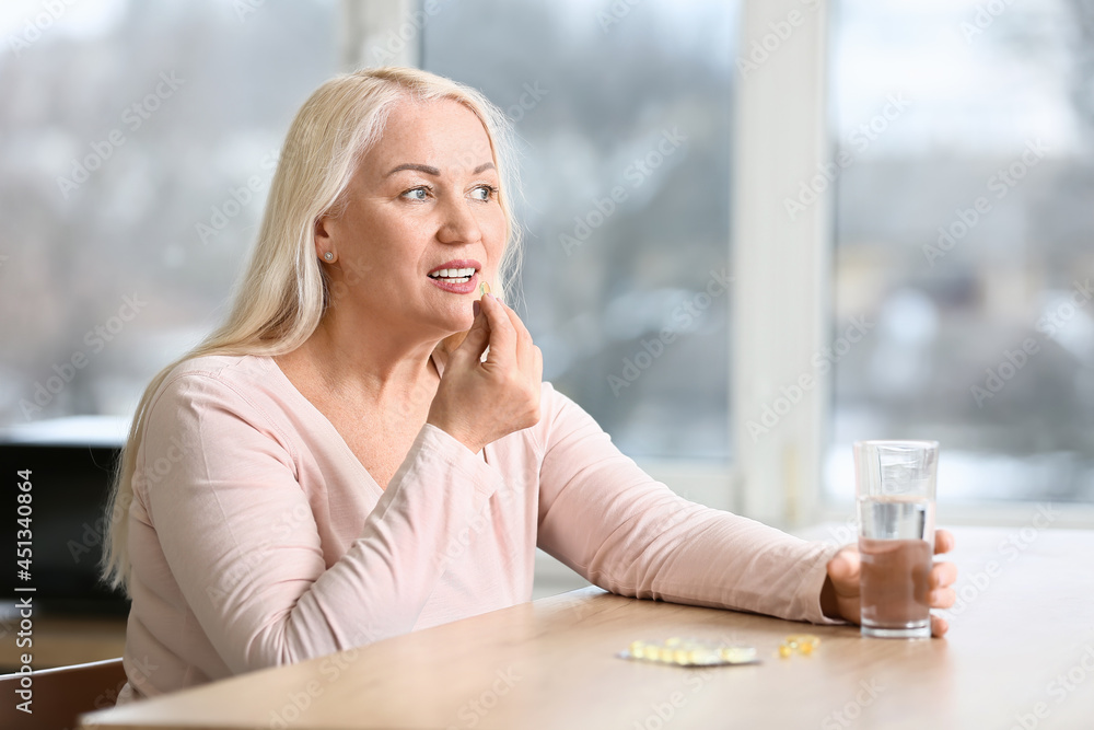 Fototapeta premium Mature woman taking fish oil at home