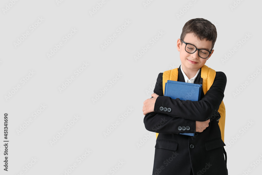 Little schoolboy with books on light background Little schoolboy with books on light background