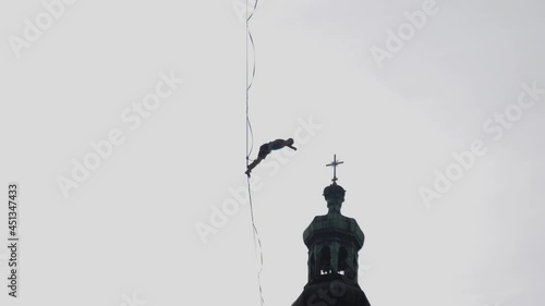 A man fail falls from a slackline hanging from a safety rope silhouette in a sky photo