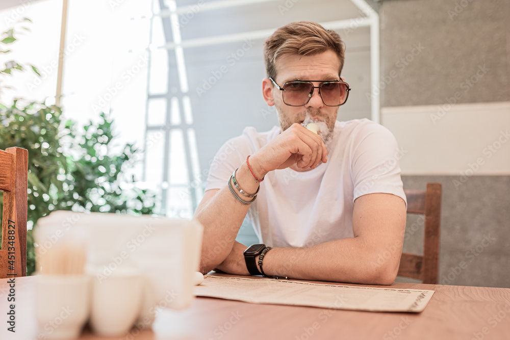 guy sits in restaurant and smokes an electronic cigarette guy sits in restaurant and smokes an electronic cigarette