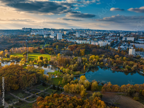 Aerial view of a lake in a park with autumn trees. Kishinev, Moldova. Epic aerial flight over water. Colorful autumn trees in the daytime.