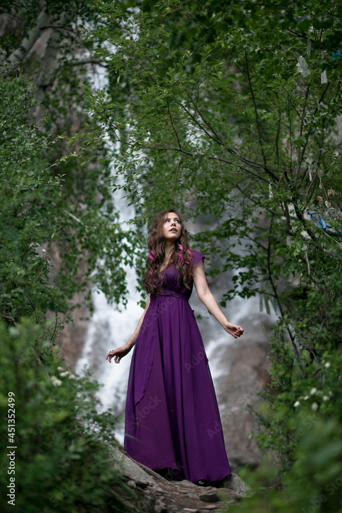 girl in a purple dress against the background of a mountain waterfall girl in a purple dress against the background of a mountain waterfall
