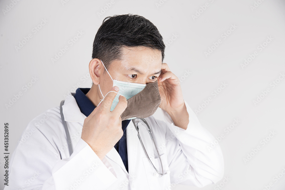 Asian doctor is wearing double layer masks for protecting Covid-19 virus - medical people working concept Asian doctor is wearing double layer masks for protecting Covid-19 virus - medical people working concept