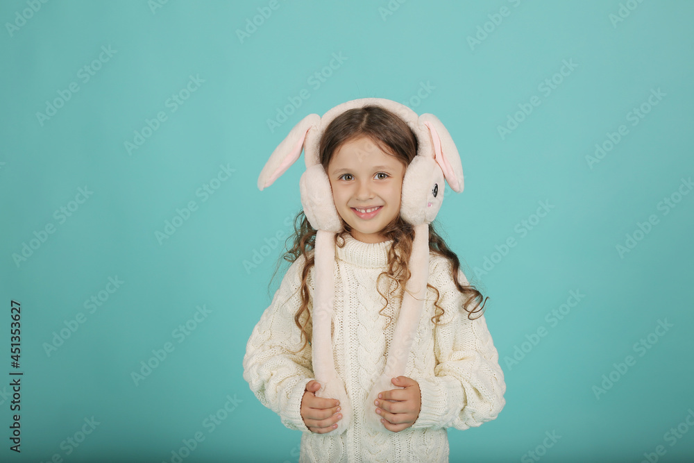 a beautiful happy brown-haired girl with curly hair in a white sweater with pink bunny ears on a blue background a beautiful happy brown-haired girl with curly hair in a white sweater with pink bunny ears on a blue background