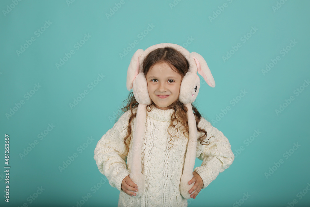 a beautiful happy brown-haired girl with curly hair in a white sweater with pink bunny ears on a blue background a beautiful happy brown-haired girl with curly hair in a white sweater with pink bunny ears on a blue background