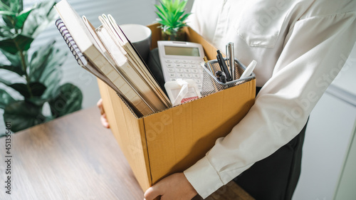 Business woman sending resignation letter and packing Stuff Resign Depress or carrying business cardboard box by desk in office. Change of job or fired from company