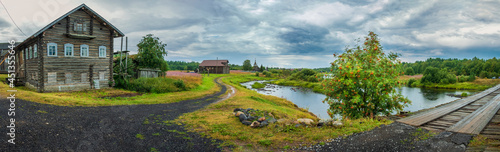 The historic village of Pyalma in Karelia Russia with old wooden houses, a bridge over the river and a church in summer.