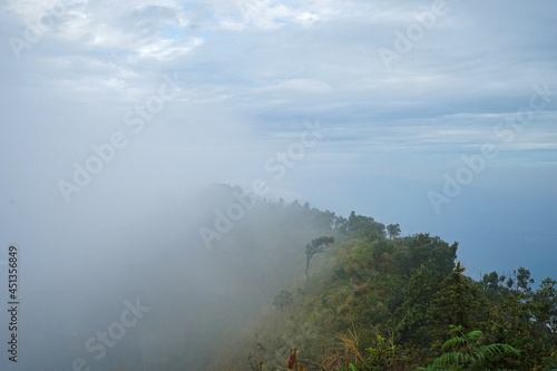 Natural landscape view from top of the green mountain range with misty and cloudy sky © chettarin
