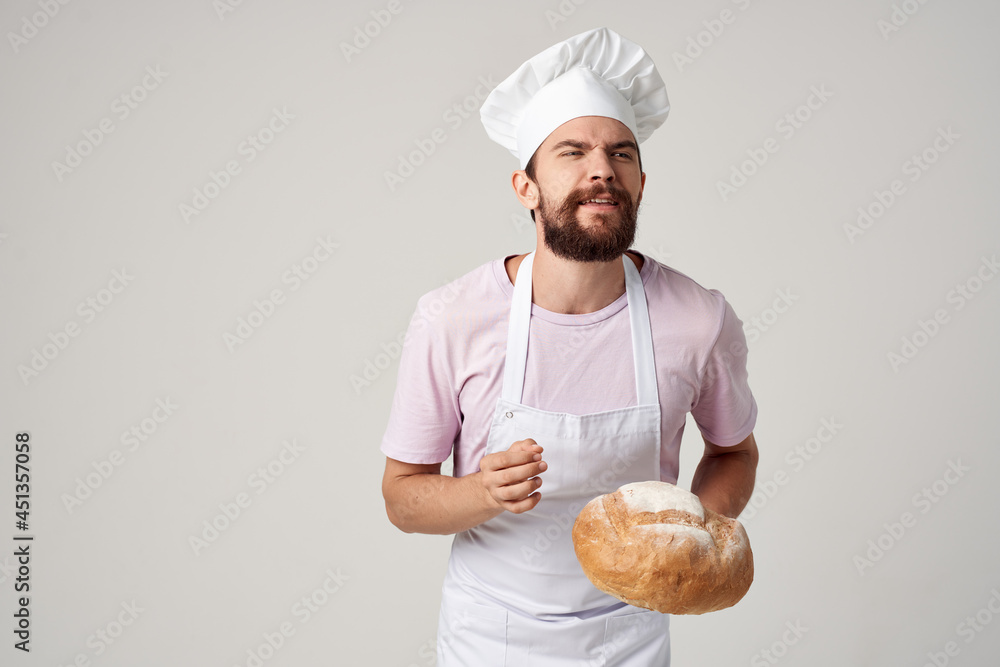 male baker in a white apron with bread in the hands of professionals male baker in a white apron with bread in the hands of professionals