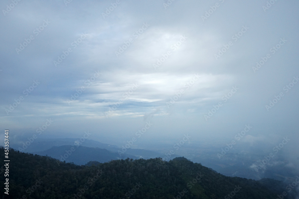 Natural landscape view from top of the green mountain range with misty and cloudy sky