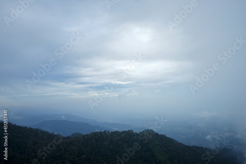 Natural landscape view from top of the green mountain range with misty and cloudy sky