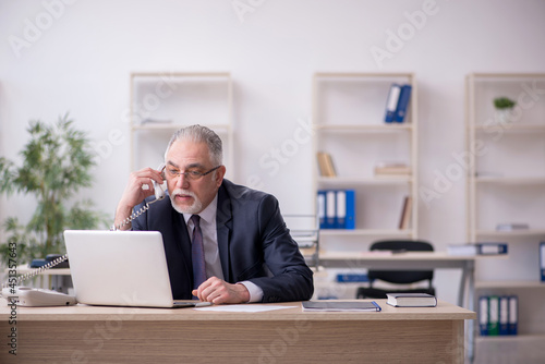 Old male employee sitting at workplace © Elnur