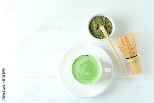 Matcha latte and accessories for making on white wooden table