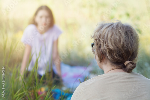 Women of European appearance are talking while sitting on the grass in the park in nature. The concept of psychological assistance, female friendship, communication, spiritual practices. Copyspace