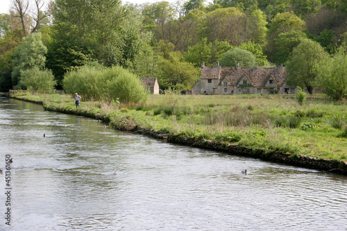 A fisherman on the banks of the River Coln in Bibury  Gloucestershire in the UK