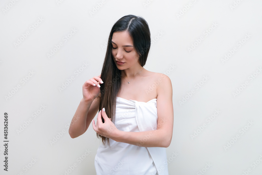 Beautiful young woman in a towel touches her hair with her hands. Beautiful young woman in a towel touches her hair with her hands.