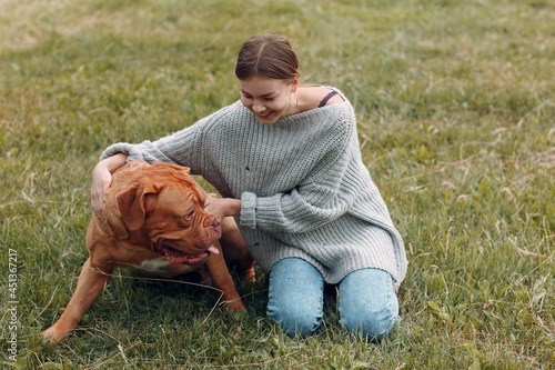 Dogue de Bordeaux or French Mastiff with young woman at outdoor park.