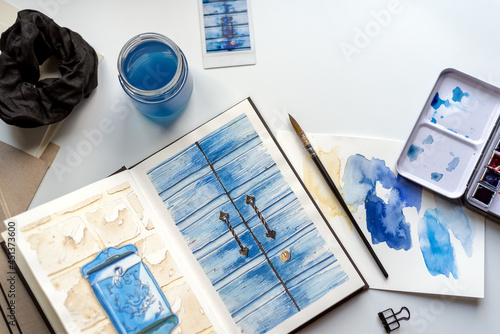 Billede på lærred An open watercolor sketchbook lies on a white table.