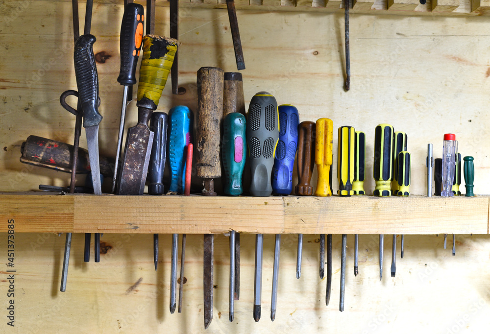 Phillips and flat screwdrivers hanging on wooden wall Phillips and flat screwdrivers hanging on wooden wall