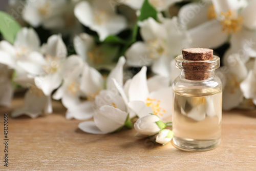 Jasmine essential oil and fresh flowers on wooden table  space for text