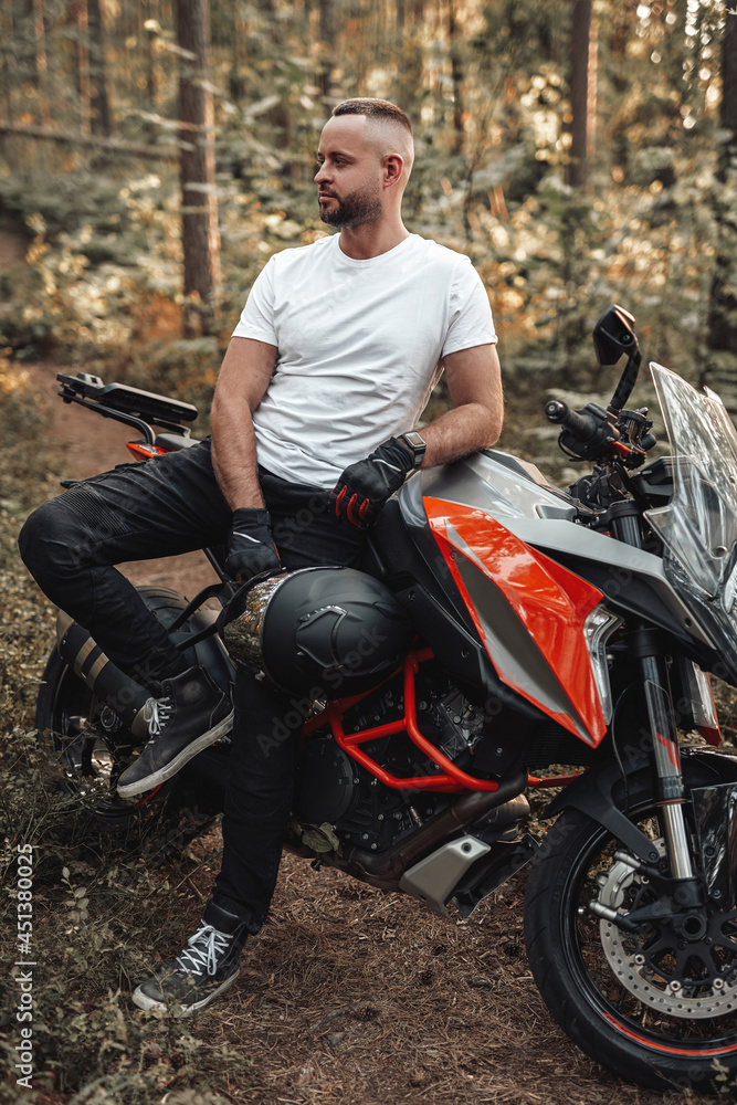 Bearded buy dressed in casual clothing with bike in forest