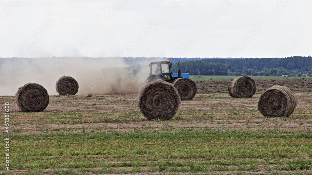 Tractor harvester and linum straw bales on the field at autumn day, linen raw harvesting in Belarus