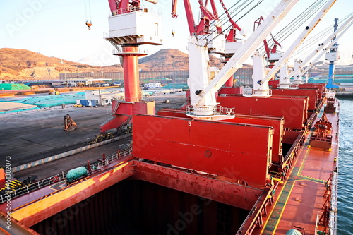 Cargo terminal for unloading bulk cargo of iron ore by shore cranes and grabs. Huludao, China, November, 2020. photo