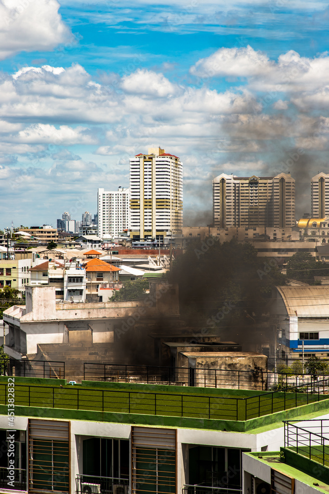 Bangkok, Thailand - 23 May, 2021 : Plume of black smoke clouds from burnt abandoned building on fire at some area in the bangkok city. Fire disaster accident, Selective focus.