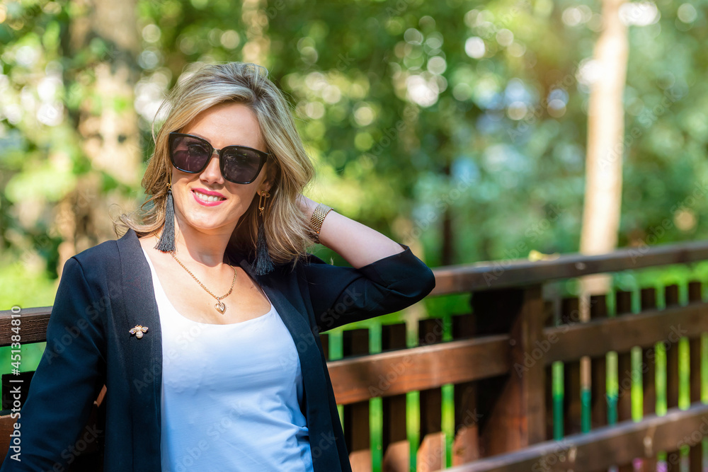 fashion portrait of a stylish nice blonde female in sunglasses on a defocused park background fashion portrait of a stylish nice blonde female in sunglasses on a defocused park background