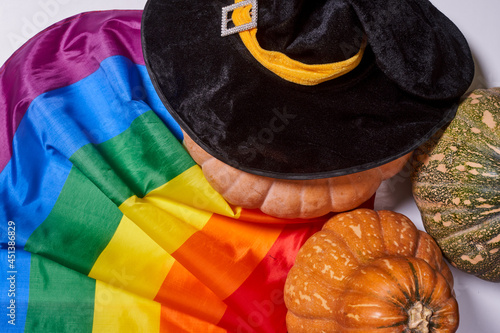 LGBTQ rainbow flag and big orange pumpkin. Halloween pumpkin with rainbow LGBT flag and black witch hat