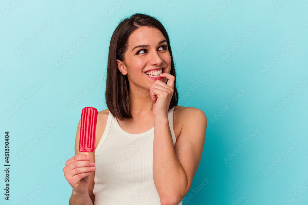 Young caucasian woman holding an ice cream isolated on blue background relaxed thinking about something looking at a copy space. Young caucasian woman holding an ice cream isolated on blue background relaxed thinking about something looking at a copy space.