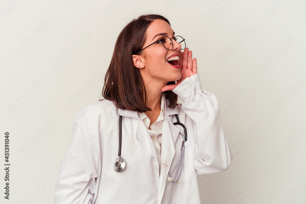 Young doctor caucasian woman isolated on white background shouting and holding palm near opened mouth. Young doctor caucasian woman isolated on white background shouting and holding palm near opened mouth.