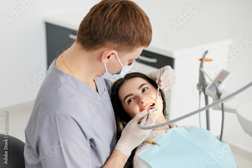 Beautiful young woman doing tooth examination in the dental office. Portrait of smiling girl on a dental chair in dentistry