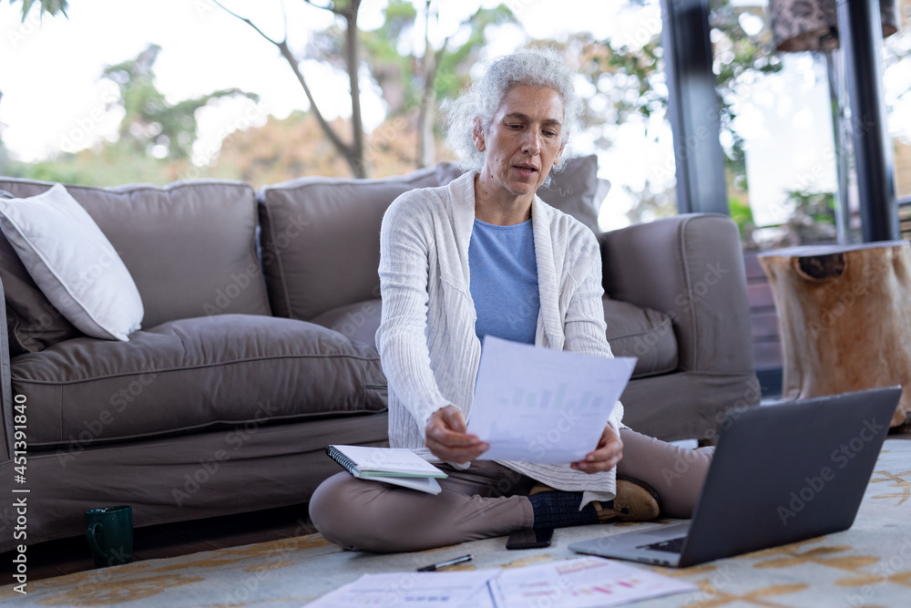 Senior caucasian woman in living room sitting on the floor and using laptop Senior caucasian woman in living room sitting on the floor and using laptop