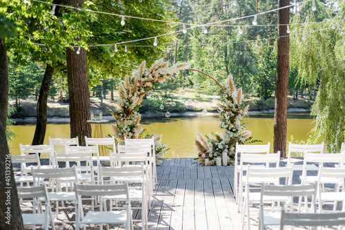 Magnificent decoration of a wedding ceremony with original details and candles. Wedding reception zone. Round arch photo