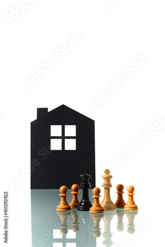 Chess pieces with silhouette of a house in the background.