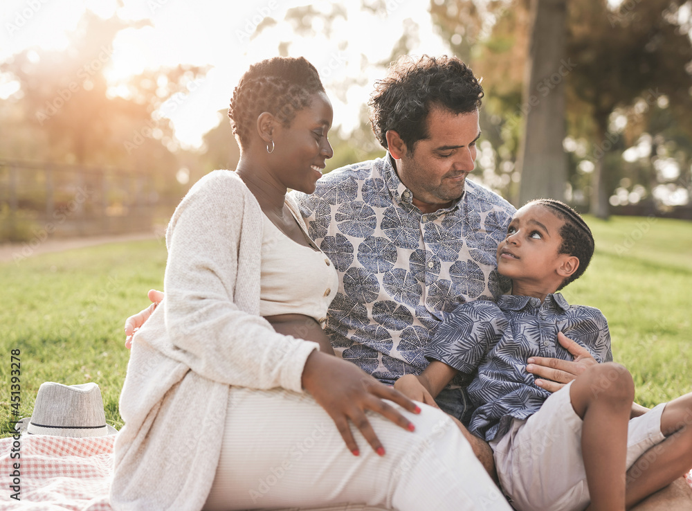 Happy multiracial family enjoy day at park - Pregnant african mother, caucasian father and mixed race son enjoy day outdoor Happy multiracial family enjoy day at park - Pregnant african mother, caucasian father and mixed race son enjoy day outdoor