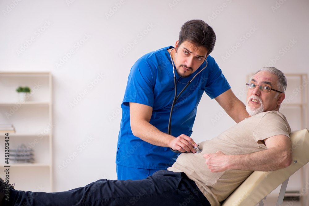 Obraz premium Old male patient visting young male doctor