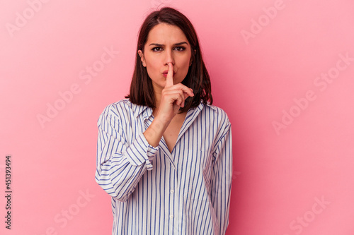 Young caucasian woman isolated on pink background keeping a secret or asking for silence. © Asier
