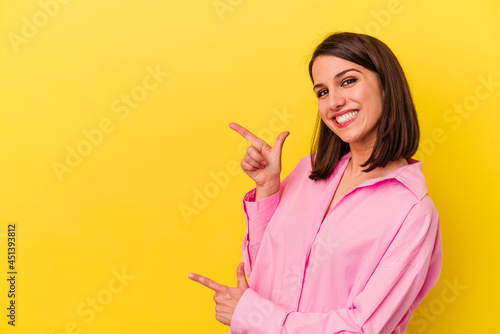 Young caucasian woman isolated on yellow background excited pointing with forefingers away.