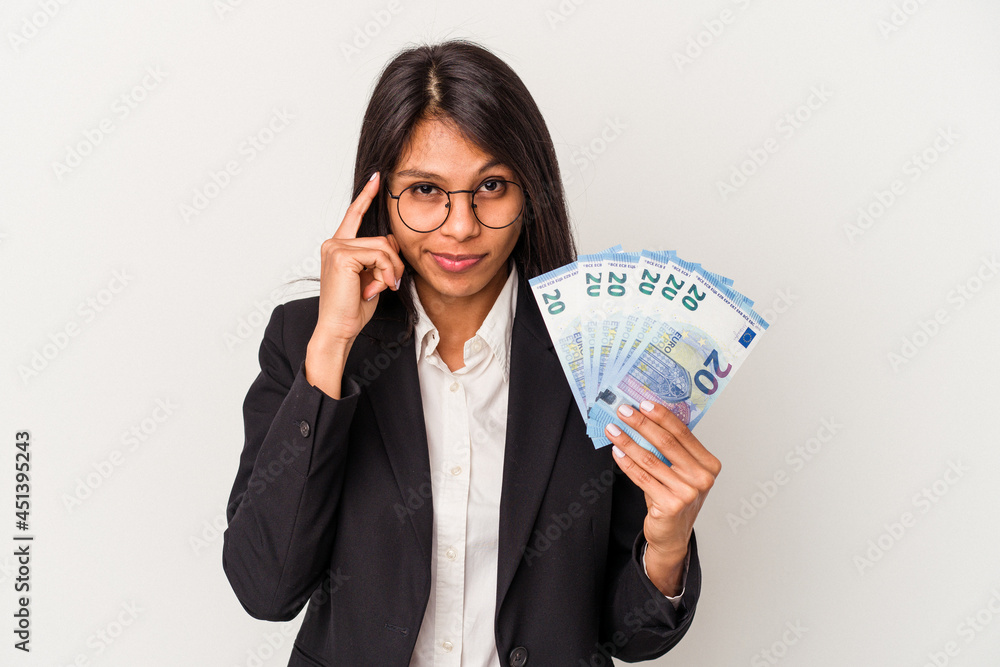 Young business latin woman holding bills isolated on white background pointing temple with finger, thinking, focused on a task. Young business latin woman holding bills isolated on white background pointing temple with finger, thinking, focused on a task.