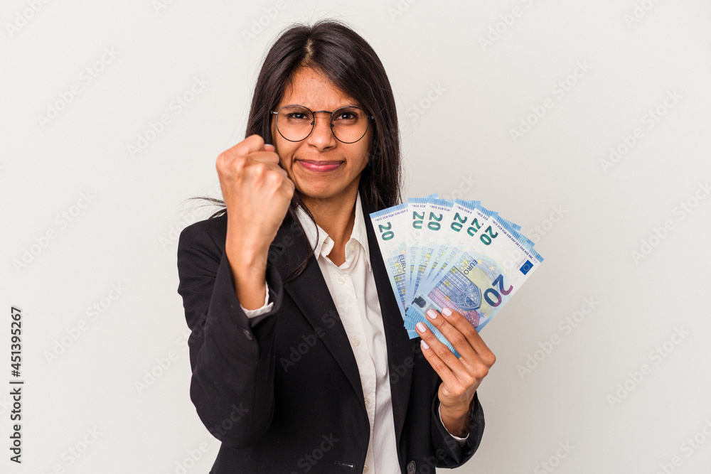 Young business latin woman holding bills isolated on white background showing fist to camera, aggressive facial expression. Young business latin woman holding bills isolated on white background showing fist to camera, aggressive facial expression.