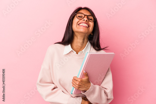 Young student latin woman isolated on pink background laughing and having fun.