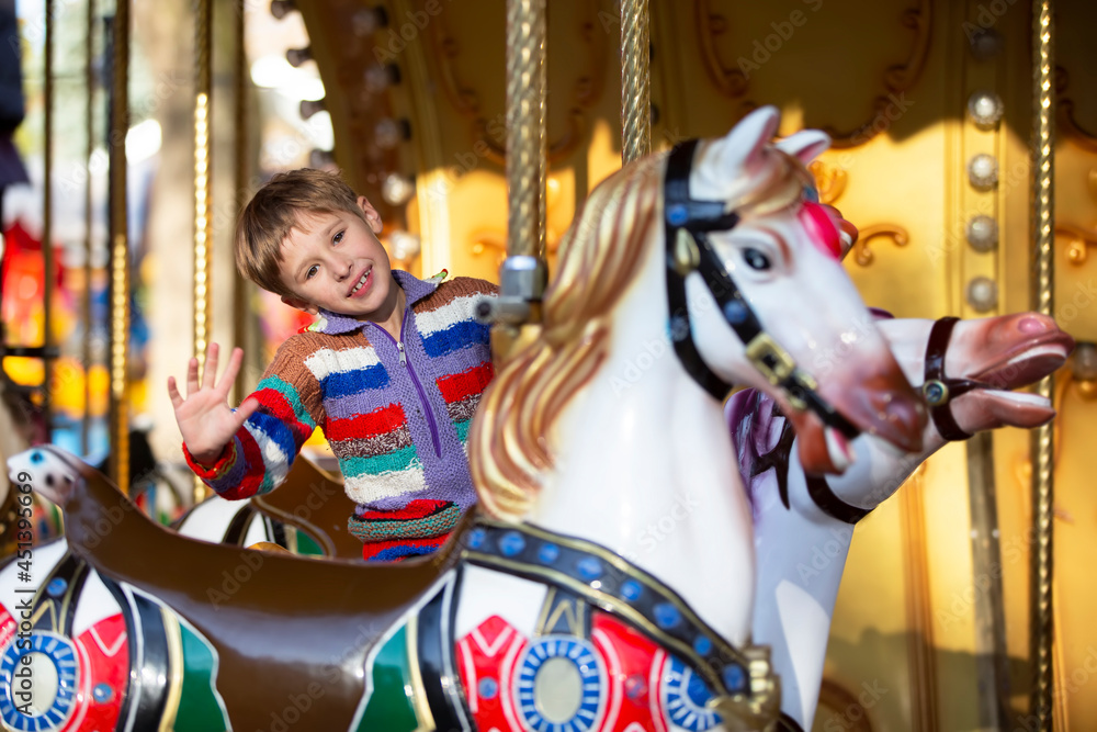 Handsome little boy is riding a carousel. A child on a horse carousel.