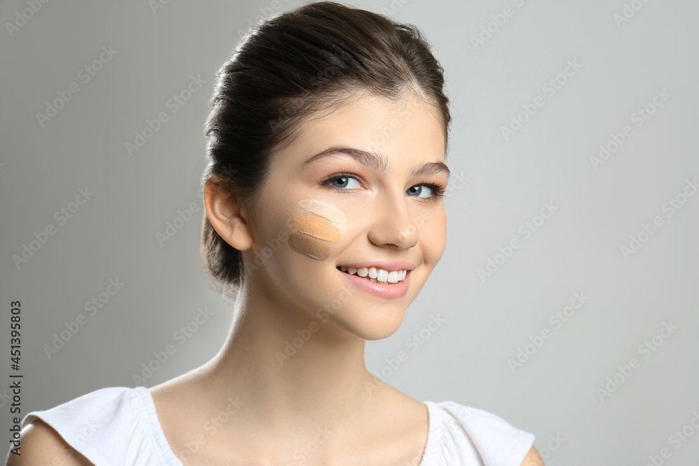 Beautiful girl on light grey background. Using concealer and foundation for face contouring Beautiful girl on light grey background. Using concealer and foundation for face contouring