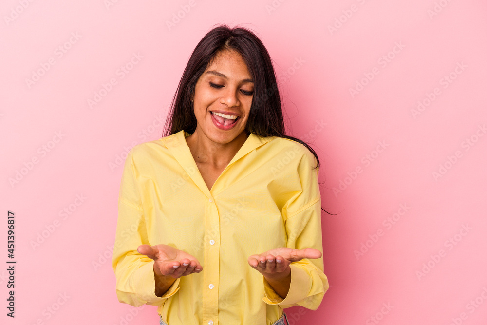 Young latin woman isolated on pink background holding something with palms, offering to camera. Young latin woman isolated on pink background holding something with palms, offering to camera.