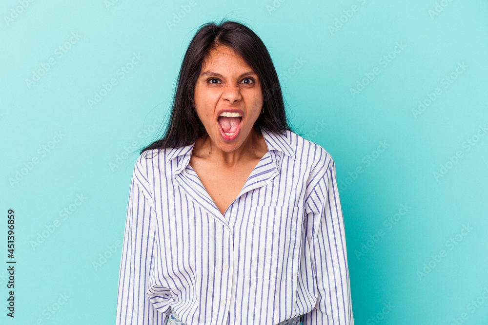 Young latin woman isolated on blue background shouting very angry, rage concept, frustrated. Young latin woman isolated on blue background shouting very angry, rage concept, frustrated.