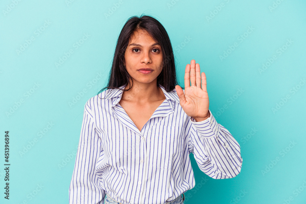Young latin woman isolated on blue background standing with outstretched hand showing stop sign, preventing you.