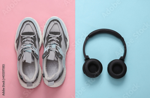 Sports shoes and headphones on blue-pink pastel background. Fitness concept. Top view. Minimalism